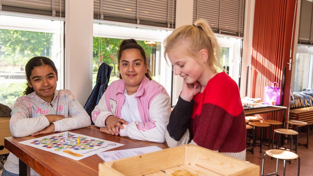 Meiden spelen het bordspel van het Platform Gehandicaptenbeleid Katwijk.