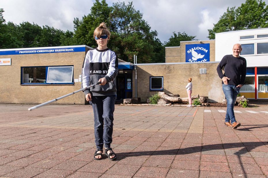 Een jongen uit groep 8 met een taststok op het schoolplein