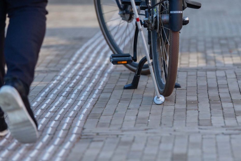 Iemand loopt met een taststok en raakt een geparkeerde fiets