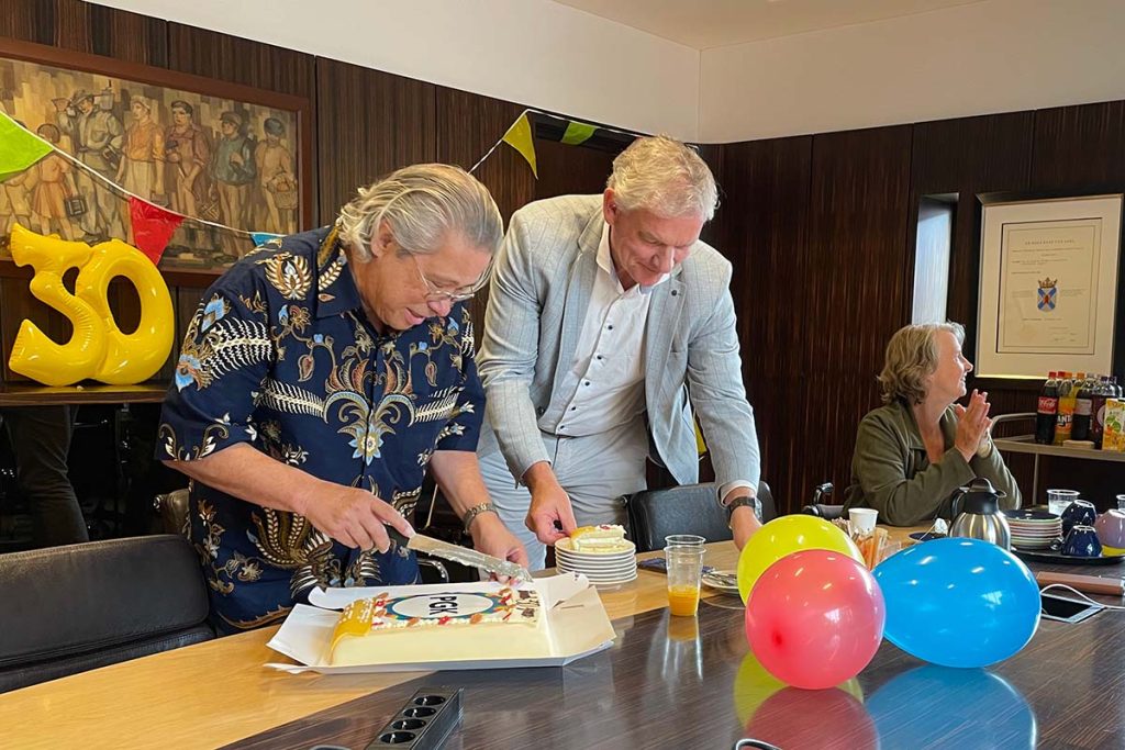 Allan snijdt de taart aan. De wethouder helpt bij het uitdelen.