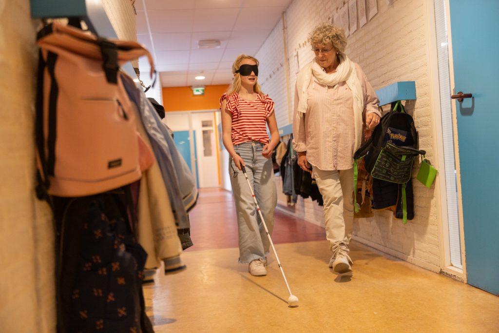 Een leerling met een taststok door de gang